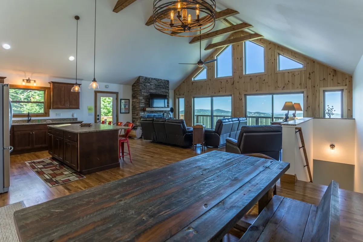 A modern, inviting space with a rustic dining table, a stylish kitchen island, comfortable seating, and floor-to-ceiling windows offering expansive mountain vistas. The layout is perfect for group meals, entertaining, or simply enjoying the scenery.